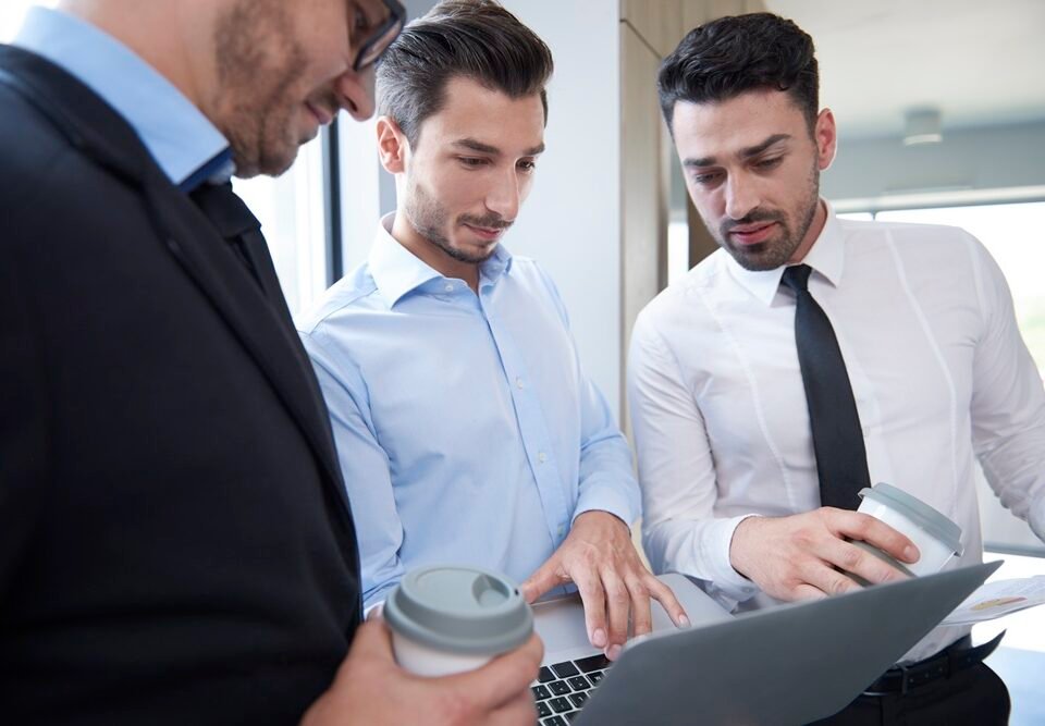 Three men over a laptop